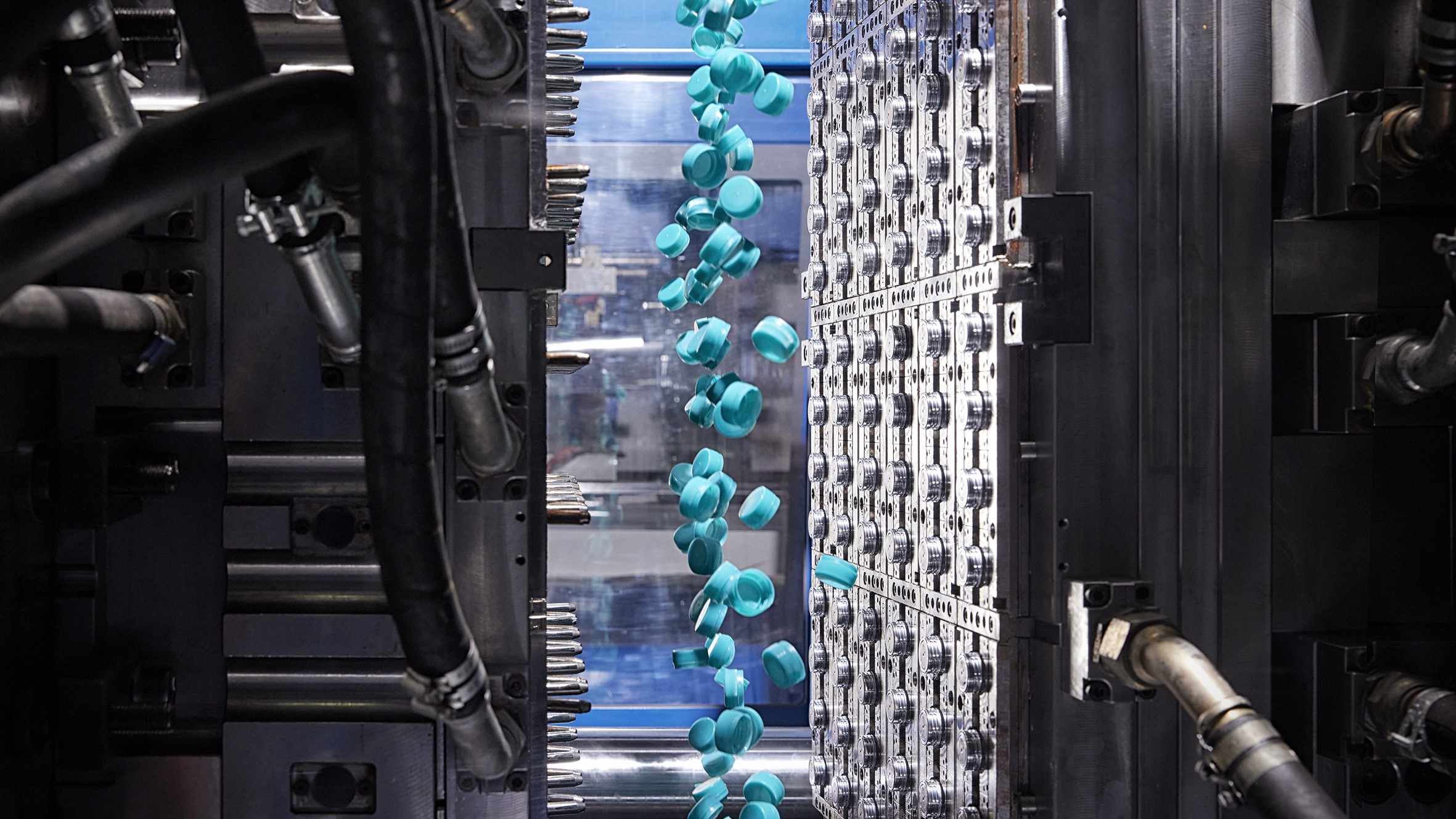 Plastic parts in blue being molded in an industrial machine.