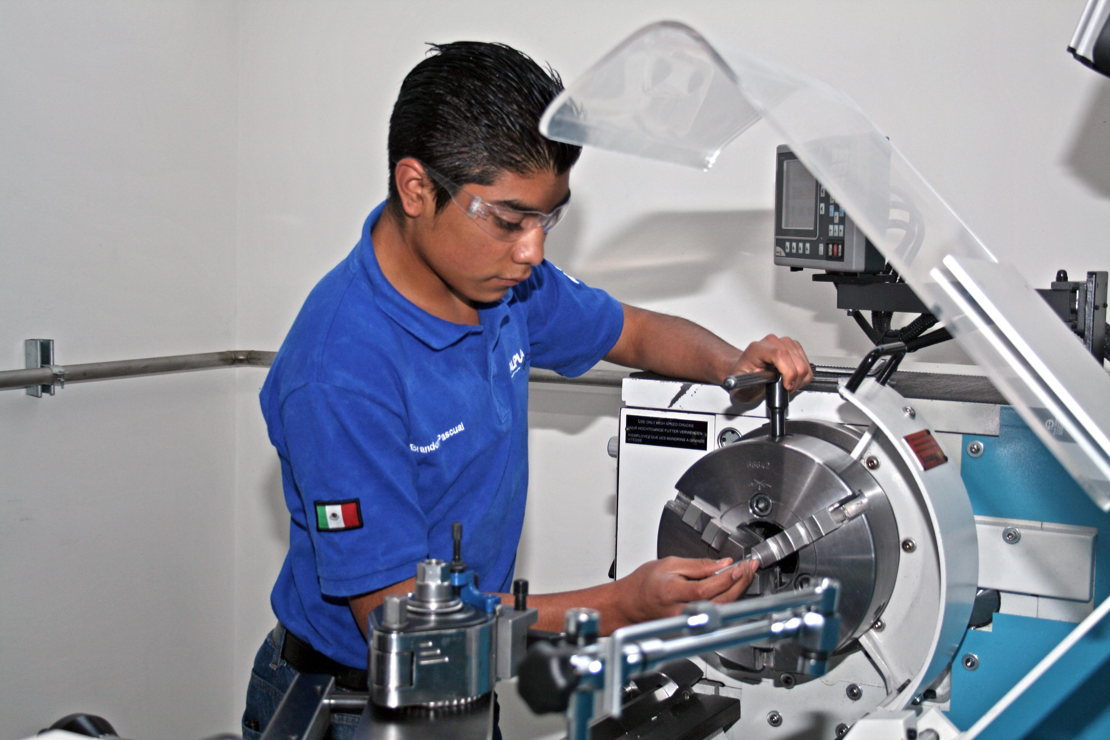Technician operating a machine in a lab, wearing a blue uniform.