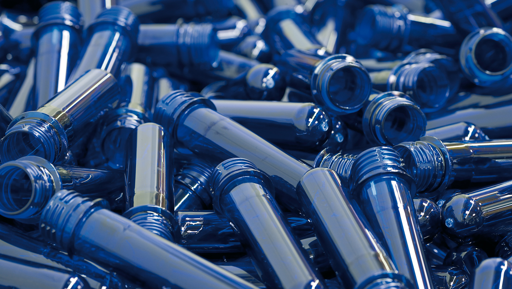 Blue plastic preforms scattered in a pile.