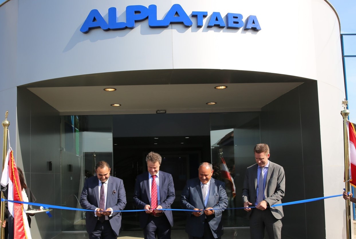 Executives cutting a blue ribbon at ALPLA Taba entrance ceremony.