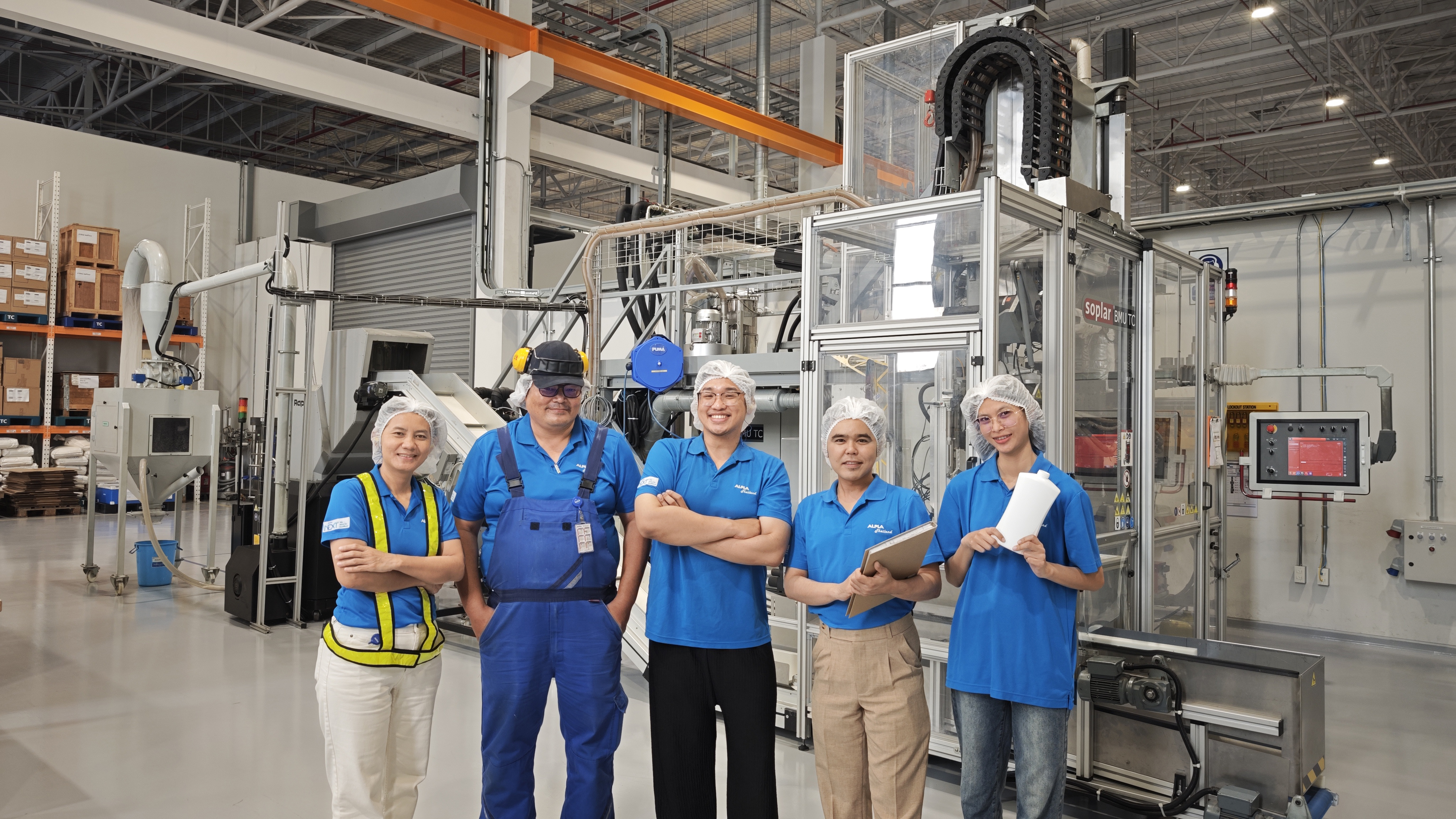 ALPLA Team in Thailand wearing hats and uniforms standing in a southeast asia manufacturing facility.