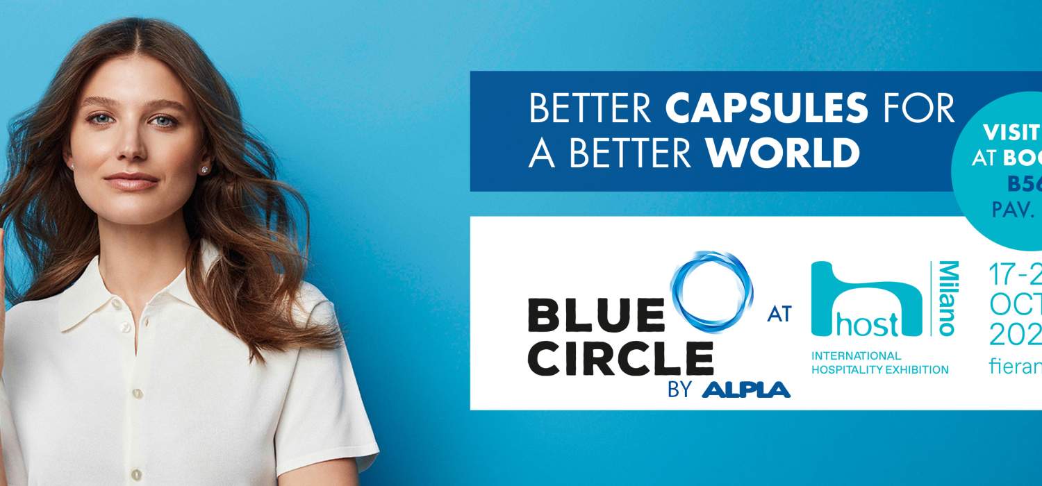 Elegant woman holding capsule next to blue ALPLA event banner.