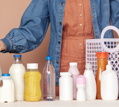 Person organizing plastic bottles on a table, with a mesh bag.