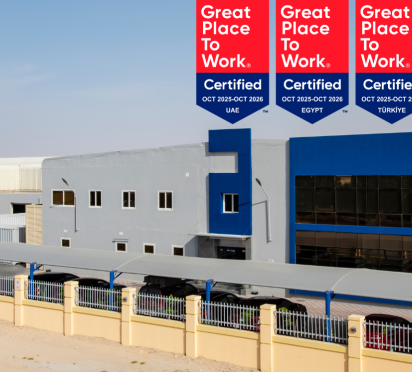 ALPLA factory exterior with blue and gray facade, desert surroundings, sunny day.