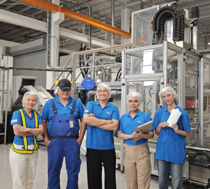 ALPLA Team in Thailand wearing hats and uniforms standing in a southeast asia manufacturing facility.