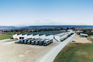 ALPLA facility with parked trucks under a clear blue sky.