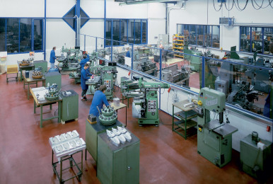 Manufacturing facility with machines and workers assembling products.