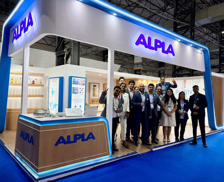 ALPLA trade show booth with a group of smiling people inside.