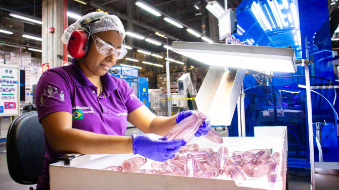 Employee inspecting plastic packaging products at an ALPLA production facility in South America