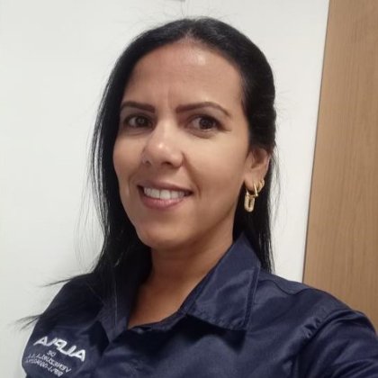 Smiling person in a dark blue ALPLA shirt indoors.