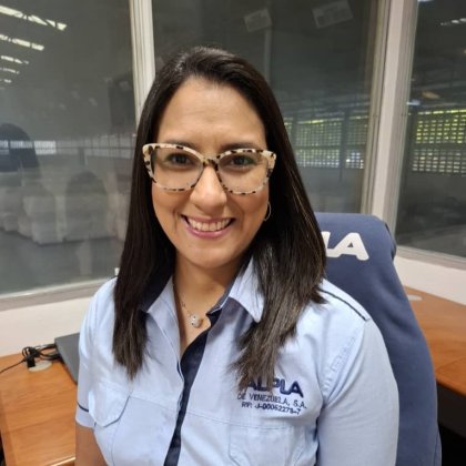 Smiling woman with glasses in ALPLA office setting.