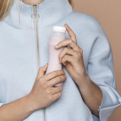 Plastic milk bottle for dairy packaging held by a consumer.